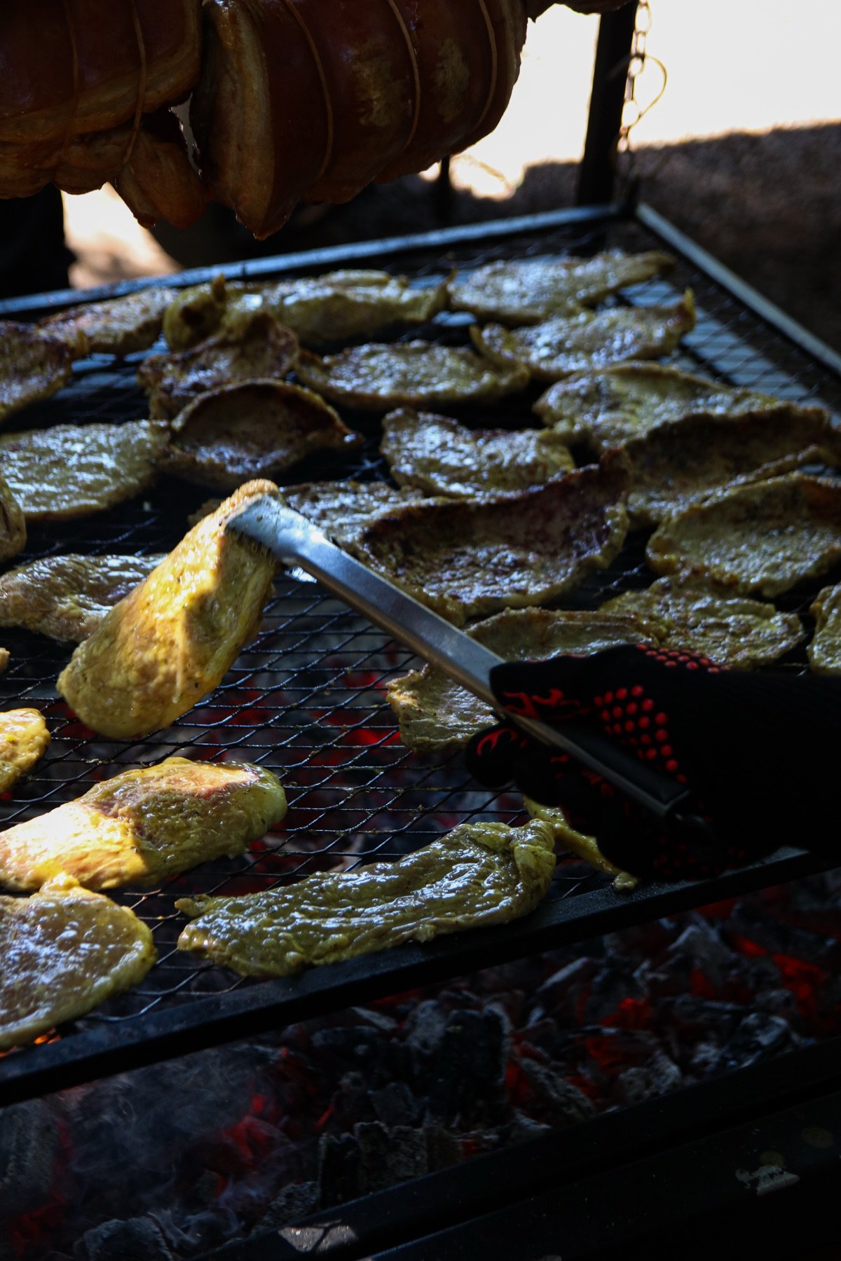 Legumes e carnes grelhando na brasa com pegador